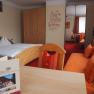 Zimmer, © Bruthenne Ein gemütliches Hotelzimmer mit einem Doppelbett, einem Sofa, einem Tisch und einem Schrank. An der Wand steht ein motivierender Spruch.