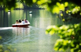 Ötschergräben im Naturpark Ötscher-Tormäuer, © weinfranz.at Vier Personen in einem Boot auf einem ruhigen See, umgeben von grüner Natur.
