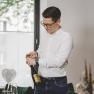 Andreas Graf leitet mit Zeitgeist und Weitblick das familiäre Restaurant, © Niederösterreich-Werbung/David Schreiber Ein Mann öffnet eine Weinflasche an einem gedeckten Tisch mit Essen.
