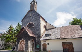 Pfarrkirche Josefsberg, © Fred Lindmoser Pfarrkirche Josefsberg mit steinverkleideter Fassade und Turm unter blauem Himmel.