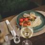 Gegrilltes Goldbrassenfilet mit Zitronenrisotto, © Niederösterreich-Werbung/David Schreiber Ein Teller mit gegrilltem Goldbrassenfilet, Zitronenrisotto und Kirschtomaten, serviert auf einem Holztisch mit einem Glas Weißwein.