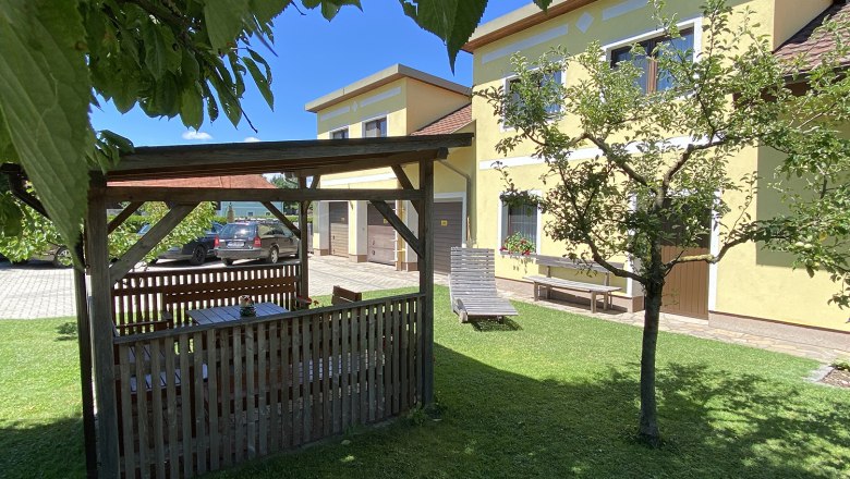 Hausansicht, © Privatzimmer Leeb Garten mit Pavillon, gelbem Haus und Auto im Hintergrund.