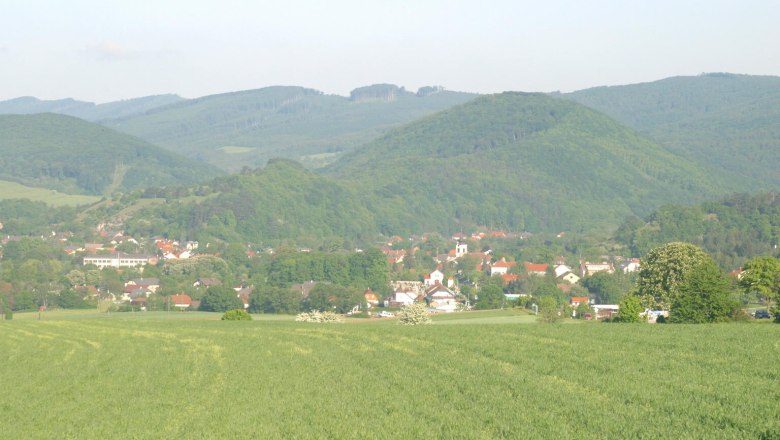 Alland Übersicht, © Wolfgang Ploy Landschaftsansicht von Alland mit grünen Feldern und bewaldeten Hügeln im Hintergrund.