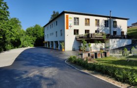 Brandtner Seminar & Komfortzimmer, © Brandtner Gebäude mit der Aufschrift 'Brandtner', umgeben von Bäumen und einem Parkplatz.