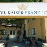 Garten Hotel Kaiser Franz Josef, © Hotel Kaiser Franz Josef Eingang des Hotel Kaiser Franz Josef mit Schild und Bäumen.