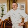 Wirt Gerhard Perthold, © Niederösterreich Werbung/Klaus Engelmayer Ein Mann in weißer Kochuniform steht lächelnd in einem Restaurant.