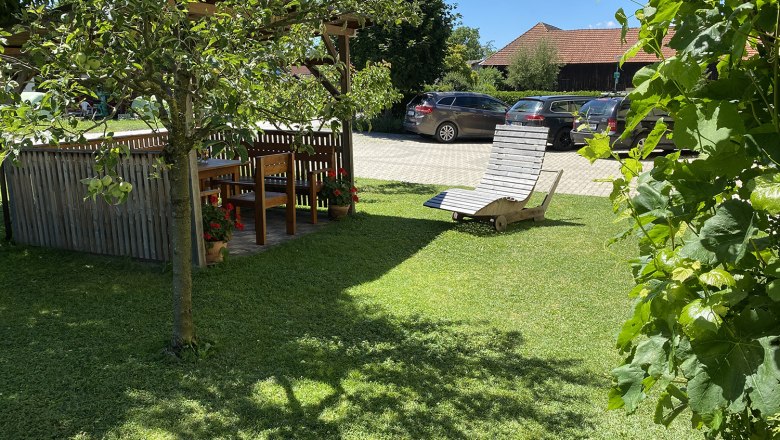 Pergola, © Privatzimmer Leeb Garten mit Pergola, Holztisch und Stühlen, Liegestuhl auf Rasen, Autos im Hintergrund.