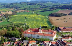 Benediktinerstift Seitenstetten, © www.stift-seitenstetten.at Luftaufnahme des Benediktinerstifts Seitenstetten umgeben von grünen Feldern und Hügeln.