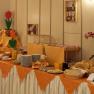 Frühstücksbuffet, © zVg Kirchenwirt Ein reichhaltiges Frühstücksbuffet mit Brot, Brötchen, Aufstrichen und Getränken auf einem Tisch mit orangefarbenem Tuch.