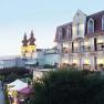 Terrassenhotel Rose, © Hotel Rose/weinfranz.at Ein Hotel mit Balkonen und einer Kirche im Hintergrund bei Dämmerung.