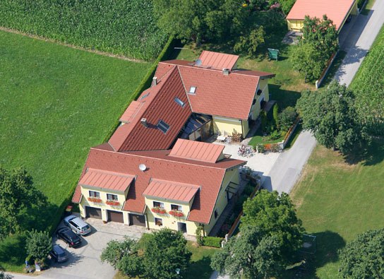 Ferienwohnungen & Privatzimmer Leeb, © Privatzimmer Leeb Luftaufnahme eines großen Hauses mit roten Dächern, umgeben von grünen Feldern und Bäumen.