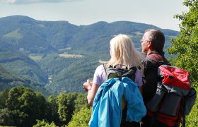Gemeinde Lilienfeld, © weinfranz.at Zwei Wanderer mit Rucksäcken blicken auf eine bergige Landschaft.