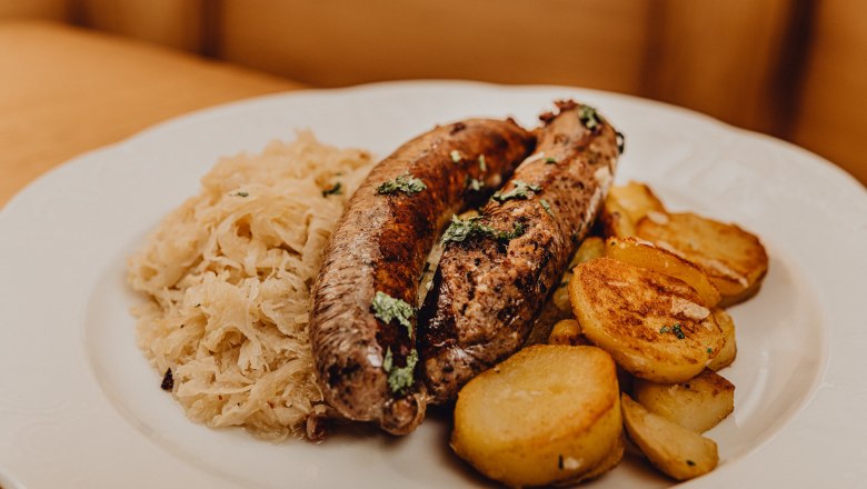 Ein Teller mit Leberwurst, Röstkartoffeln und Sauerkraut.
