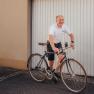 Mann in weißem Polohemd fährt Fahrrad vor Garagentor.