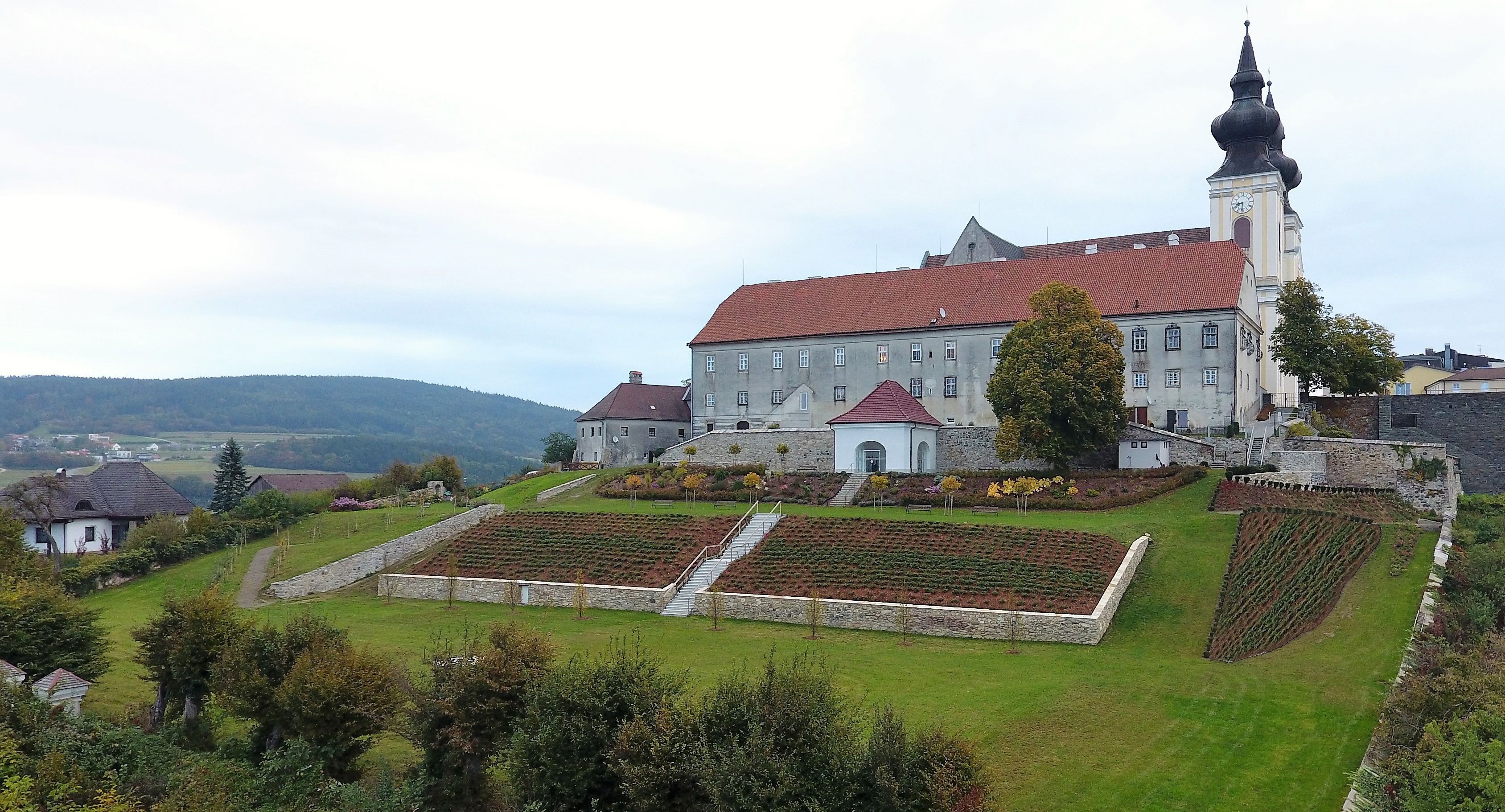 Landschaft mit Kirche und Gartenanlage auf einem Hügel.