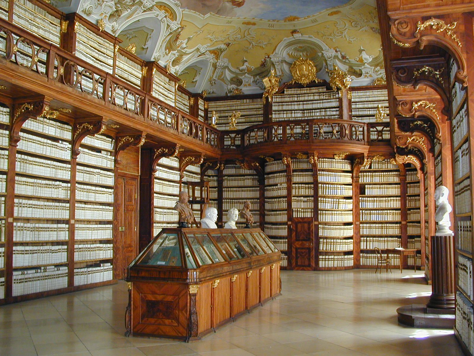 Innenansicht der Bibliothek im Stift Seitenstetten mit reich verzierten Holzregalen und Büsten.