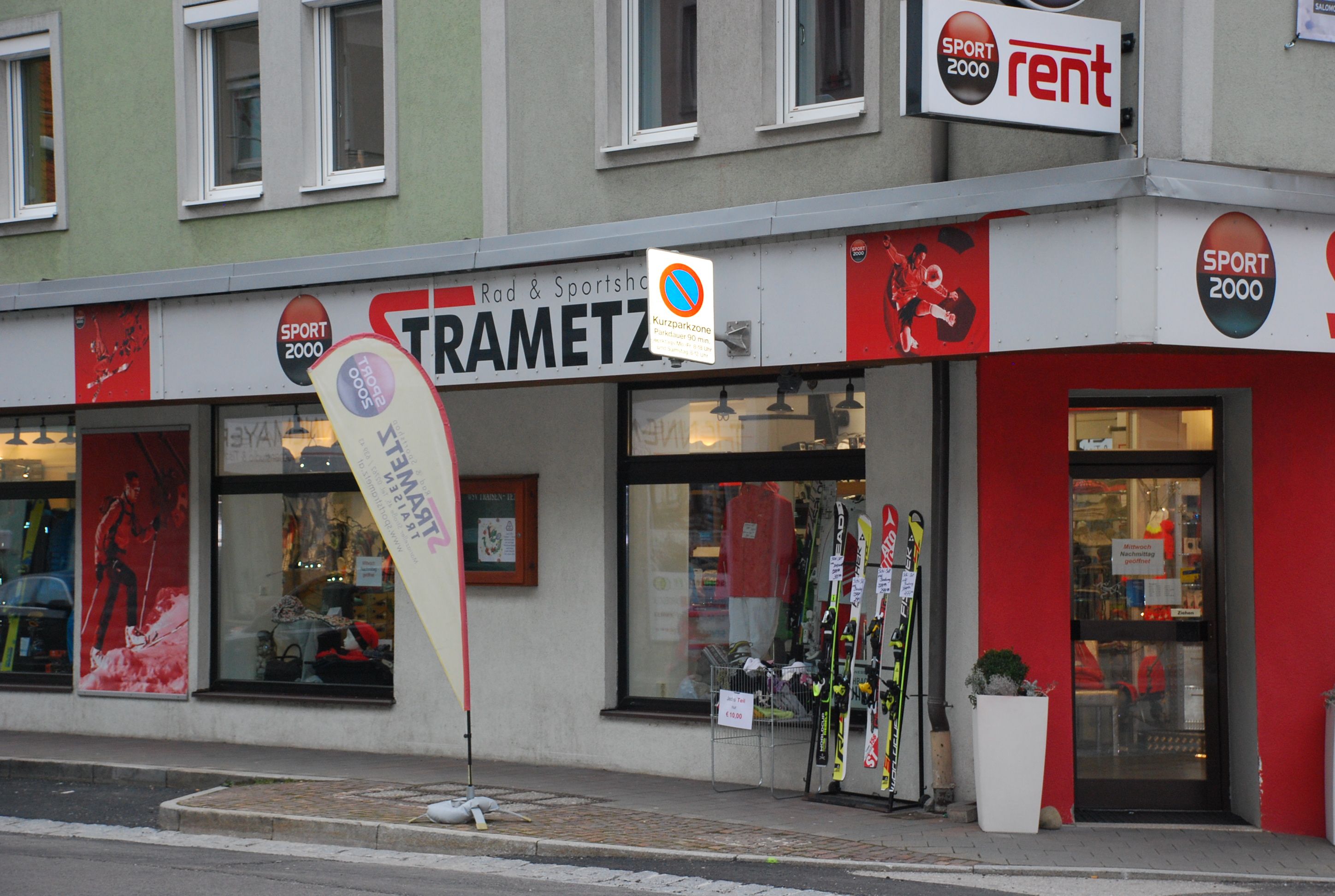 Außenansicht eines Sportgeschäfts namens Strametz mit Skiern und Sportbekleidung im Schaufenster.