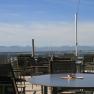 Terrasse mit Tischen und Stühlen, im Hintergrund Alpenpanorama.