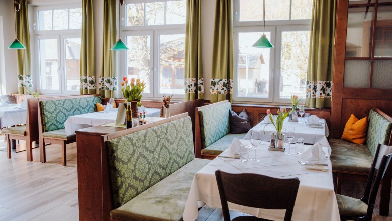 Gemütliches Restaurant mit grünen Sitzbänken und Tischdekoration.