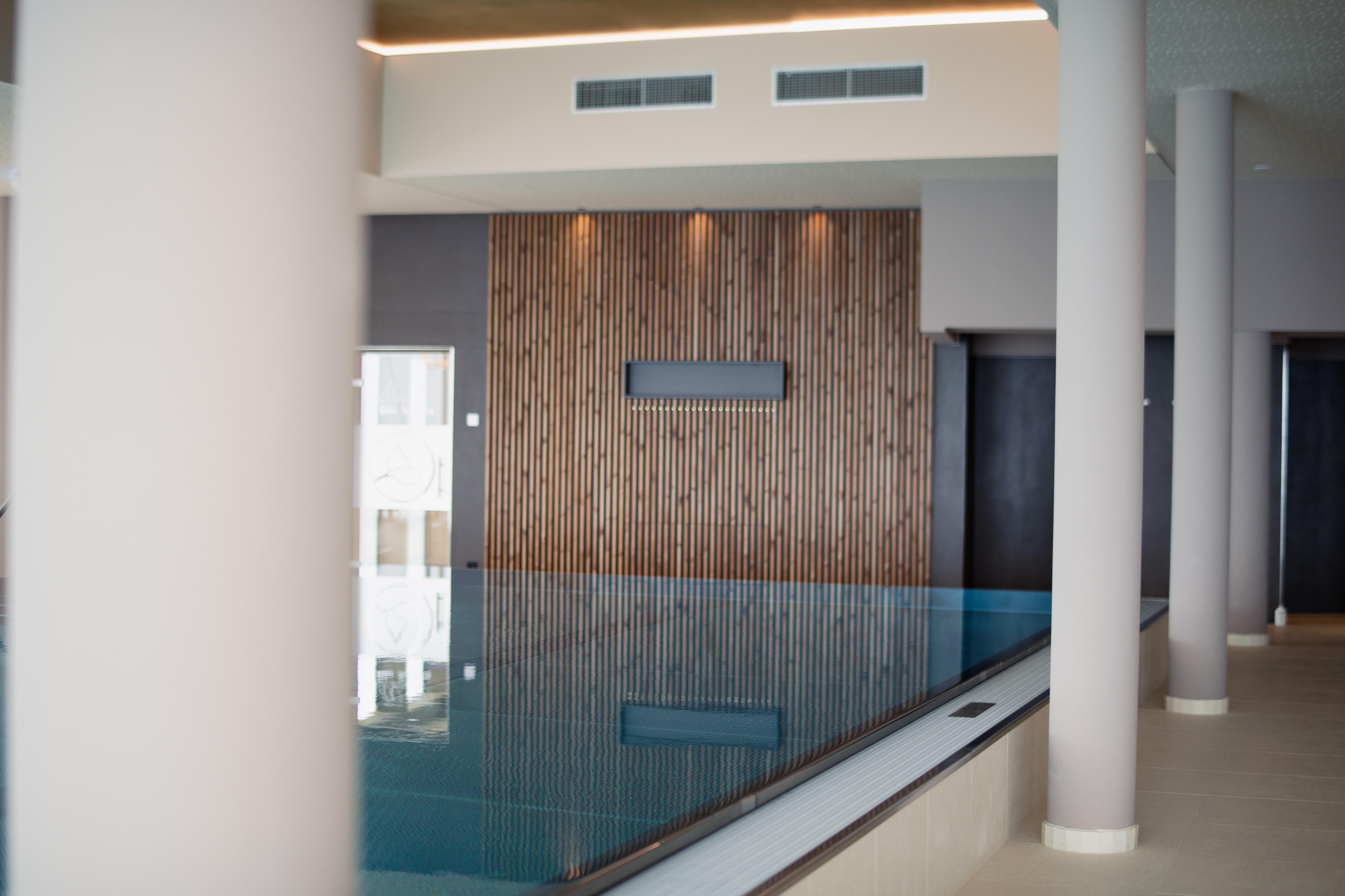 Innenansicht eines Infinitypools im Hotel Schachner mit Holzverkleidung und modernen Säulen.