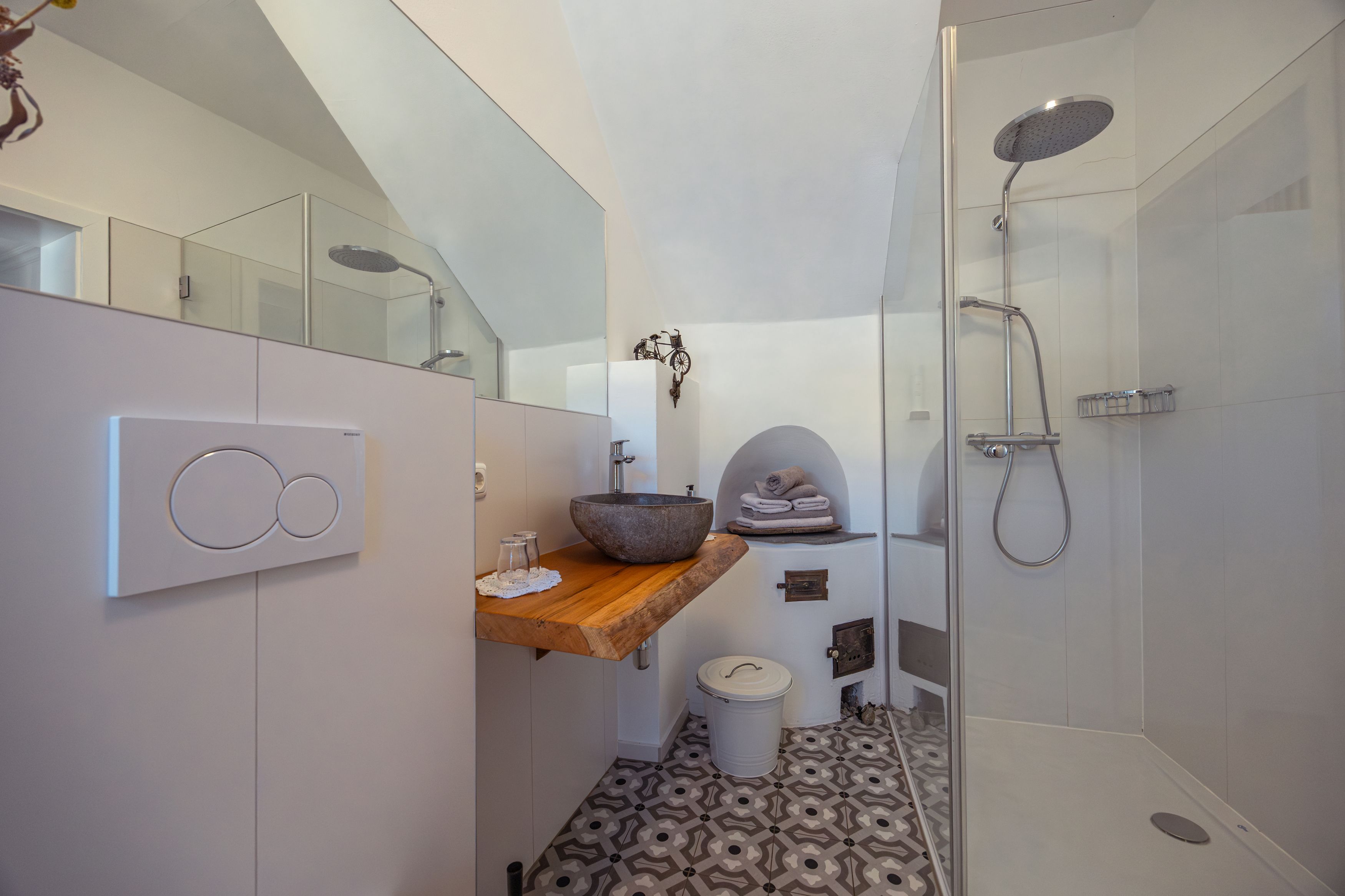 Modernes Badezimmer mit Glasdusche, Steinwaschbecken und gemustertem Boden.