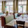 Gem&uuml;tliches Restaurant mit gr&uuml;nen Sitzb&auml;nken und Tischdekoration.