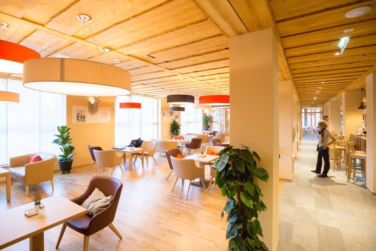 Lobby des JUFA Hotels Annaberg mit modernen Möbeln und großen Lampen.