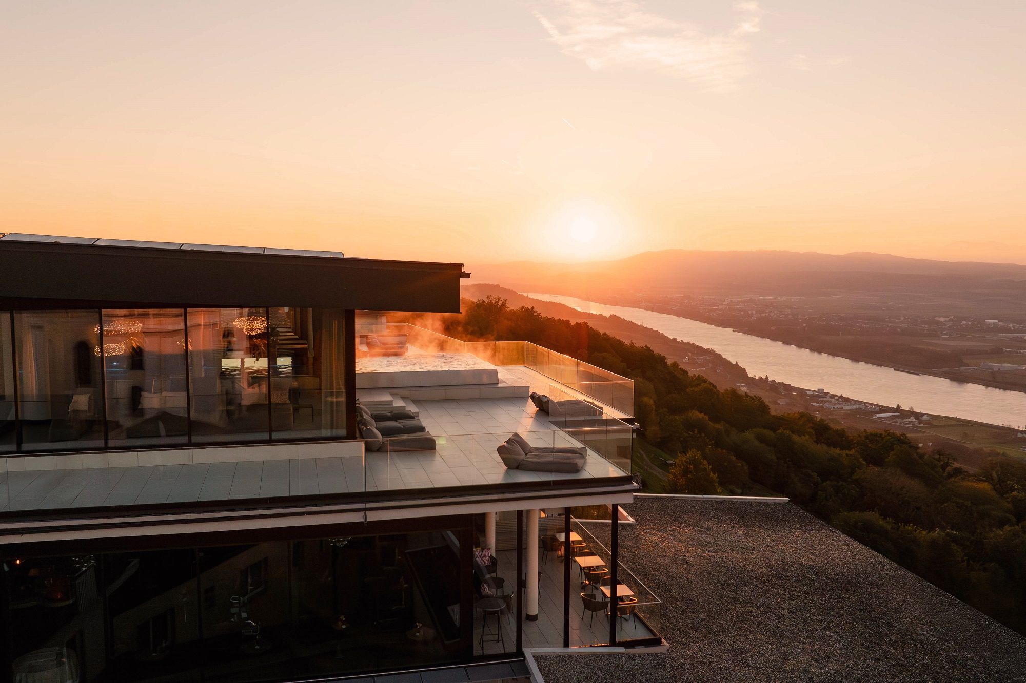 Modernes Hotel mit Terrasse und Flussblick bei Sonnenuntergang und Blick über die Donau.
