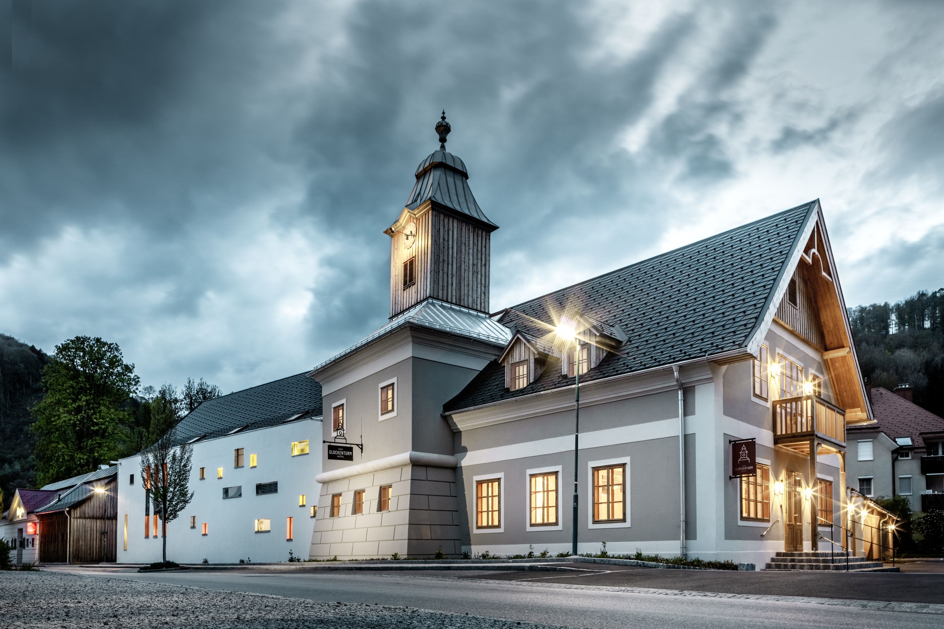 Ein Hotel mit Glockenturm bei bewölktem Himmel, beleuchtet von Straßenlaternen.
