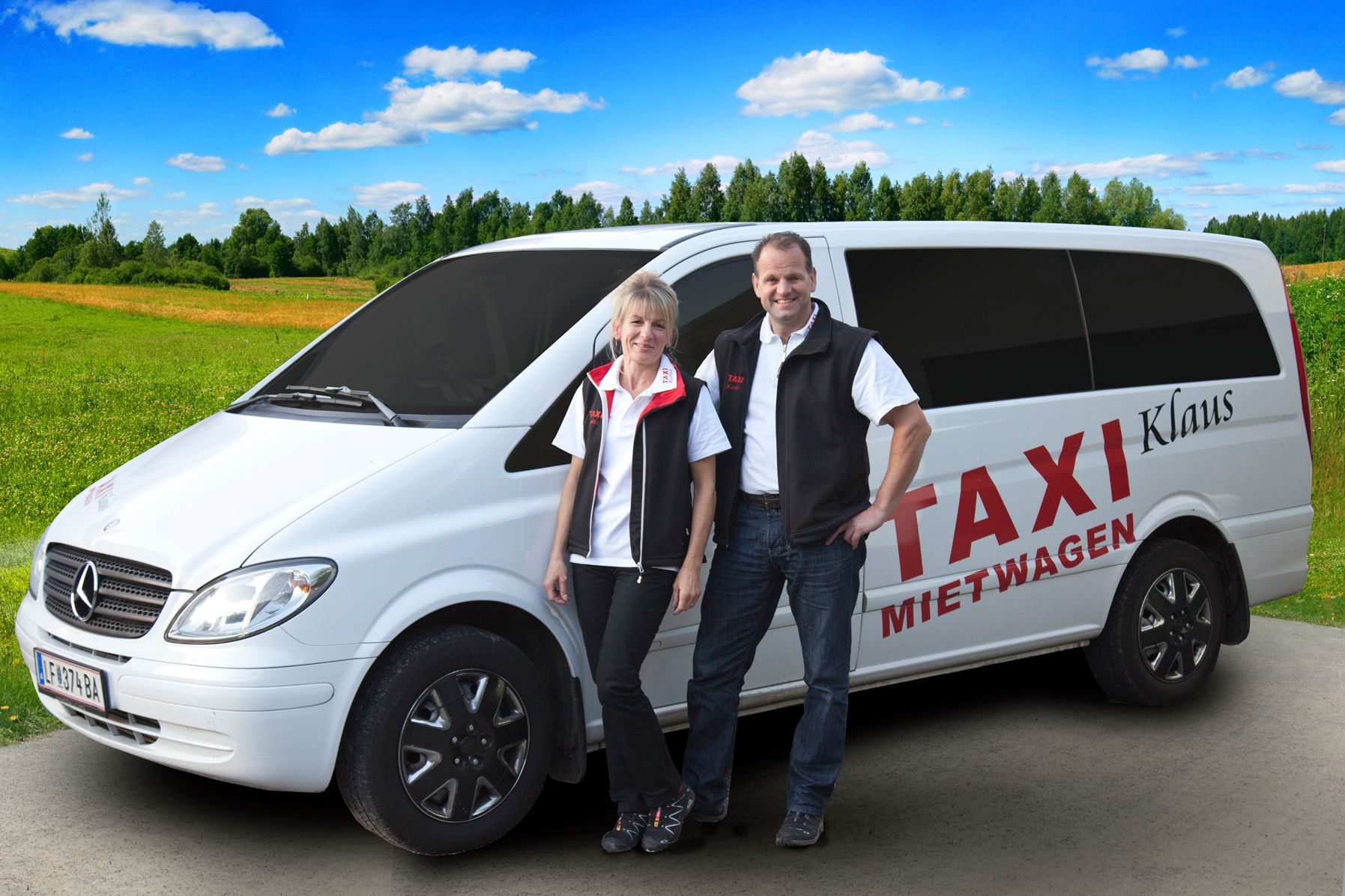 Zwei Personen stehen vor einem weißen Mercedes-Van mit der Aufschrift 'Taxi Mietwagen Klaus' auf einer ländlichen Straße.