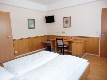 Ein Hotelzimmer mit Doppelbett, Schreibtisch, Stuhl und Wanddekoration.