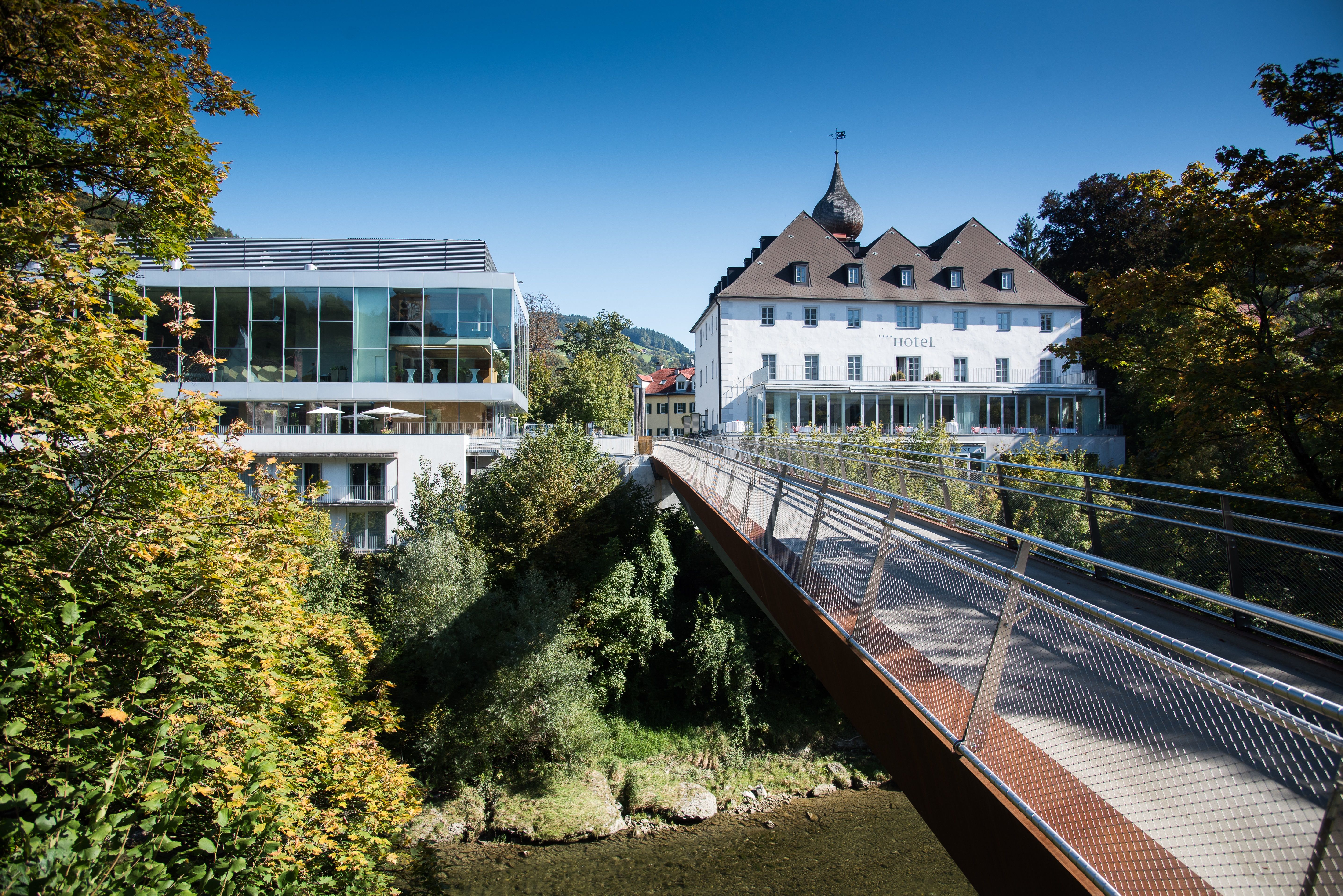 Moderne und historische Gebäude mit Brücke in grüner Umgebung.