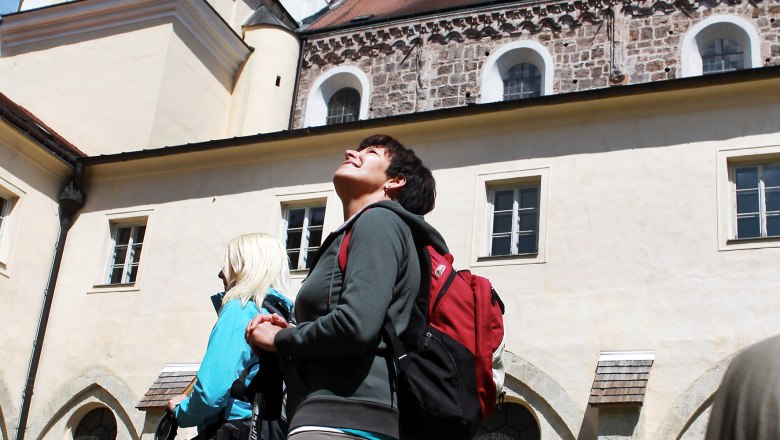 Zwei Personen mit Rucksäcken und Wanderstöcken stehen vor dem Stift Lilienfeld und schauen nach oben.