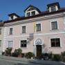 Au&szlig;enansicht eines rosa Hauses mit wei&szlig;en Fensterrahmen und einer gelben Fahne.