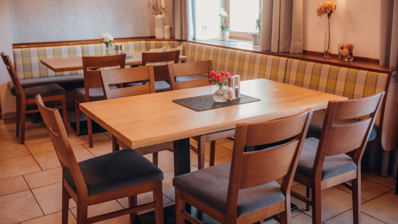 Gemütliches Restaurant mit Holztischen und gepolsterten Sitzbänken.