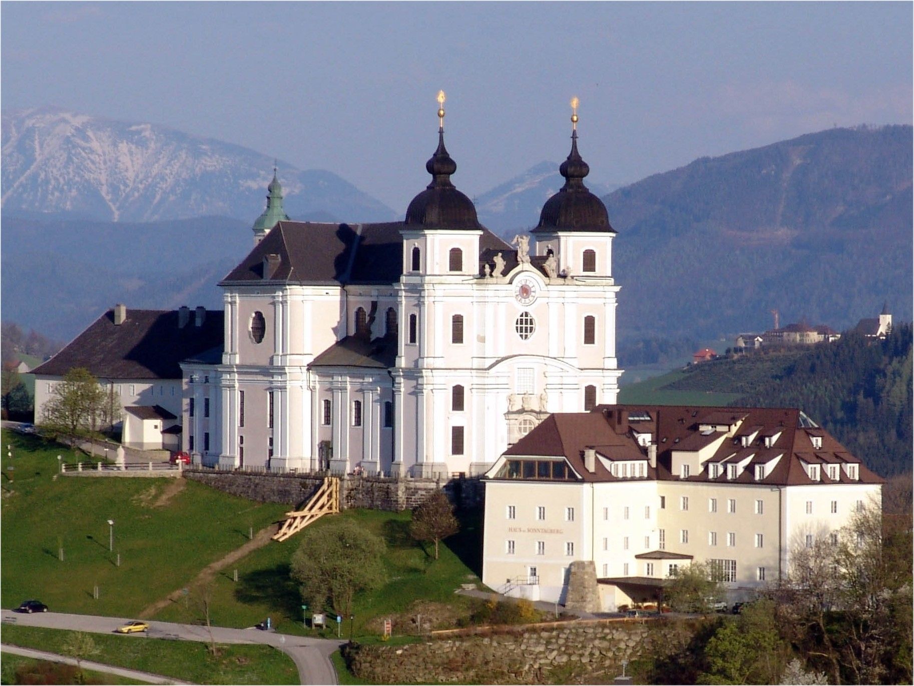 Basilika Sonntagberg auf einem Hügel mit Bergen im Hintergrund.