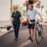 Zwei Personen unterhalten sich, w&auml;hrend einer ein Fahrrad schiebt.