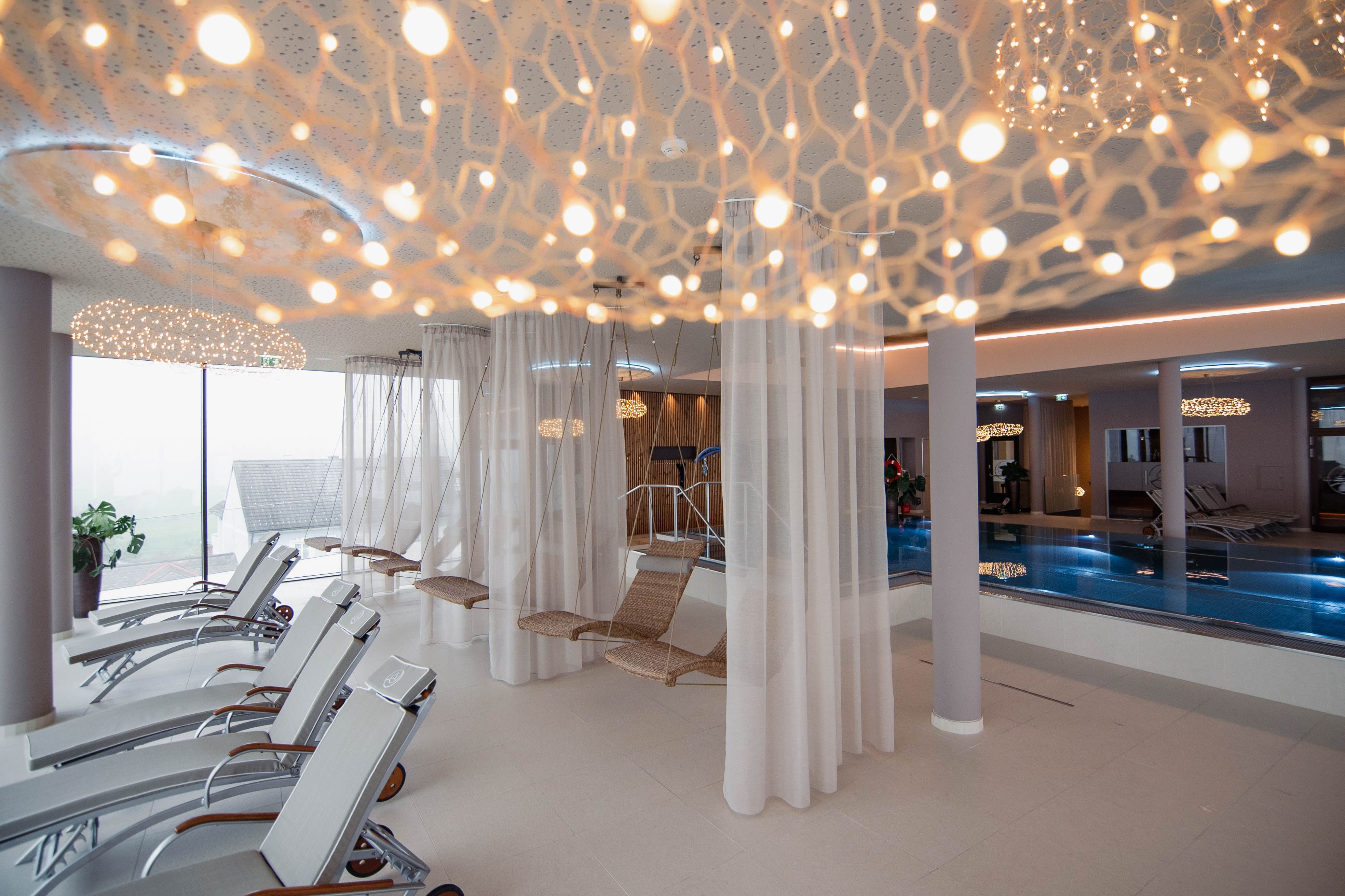 Moderner Spa-Ruhebereich mit Liegestühlen, Hängesesseln und Pool.