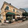 Au&szlig;enansicht eines gelben Gasthauses mit Terrasse und Sonnenschirmen.