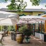 Au&szlig;enbereich eines Restaurants mit Tischen, St&uuml;hlen und Sonnenschirmen.