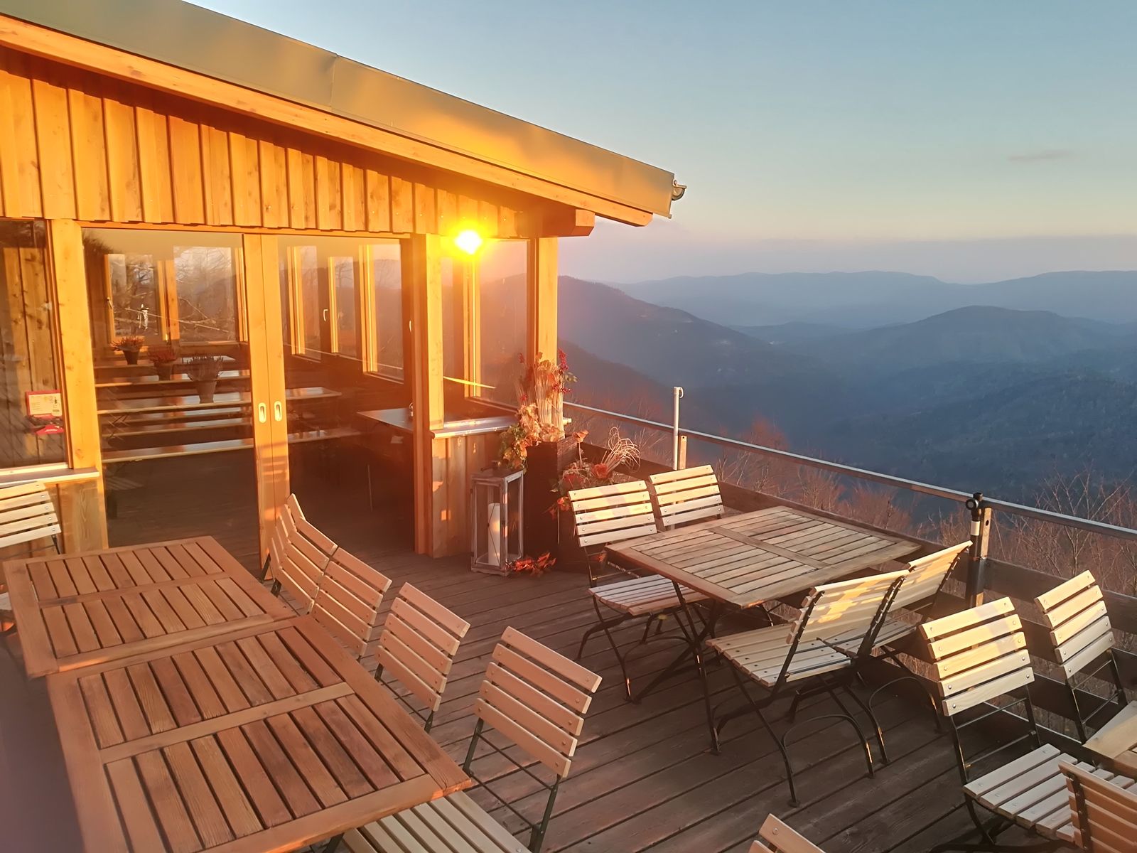 Terrasse mit Holzmöbeln und Bergblick bei Sonnenuntergang.