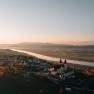 Luftaufnahme einer Kirche bei Sonnenuntergang, umgeben von Fluss und Landschaft.