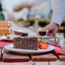 Mohnkuchen mit Erdbeere und Espresso auf einem Holztisch im Freien serviert.