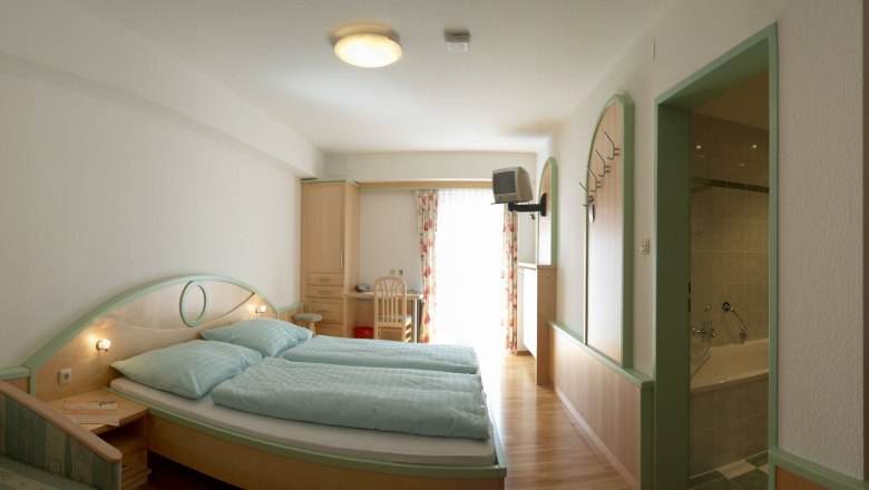 Ein Hotelzimmer mit Doppelbett, Schreibtisch, Fernseher und Badezimmer.