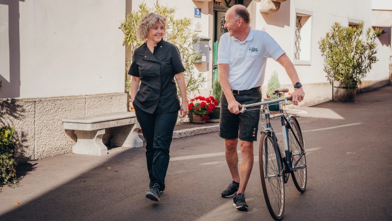 Zwei Personen unterhalten sich, während einer ein Fahrrad schiebt.