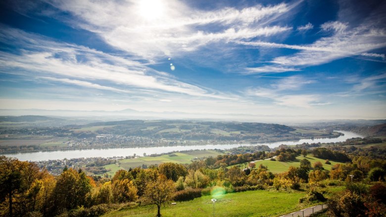 Panoramablick auf eine Flusslandschaft mit grünen Feldern und blauem Himmel.