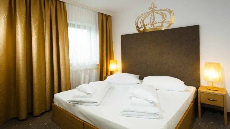 Ein Doppelzimmer mit einem großen Bett, goldenen Vorhängen und zwei Nachttischen mit Lampen.