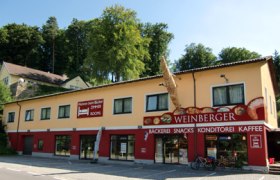 Au&szlig;enansicht einer B&auml;ckerei mit gelber Fassade und rotem Schild.
