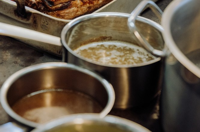 Braten in einer Auflaufform mit Töpfen auf einem Herd in der Küche.