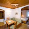 Gem&uuml;tliches Hotelzimmer mit Holzm&ouml;beln, Esstisch, Sofa und Doppelbett.